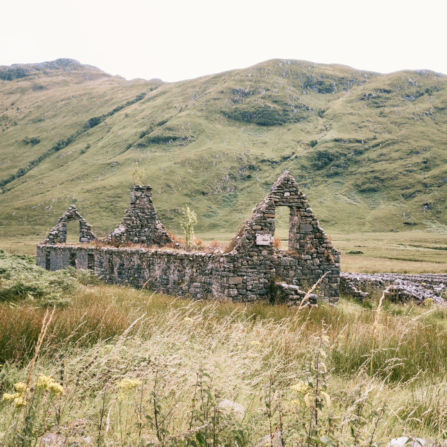 An old farm building with no roof or windows in a grassy valley in scotland