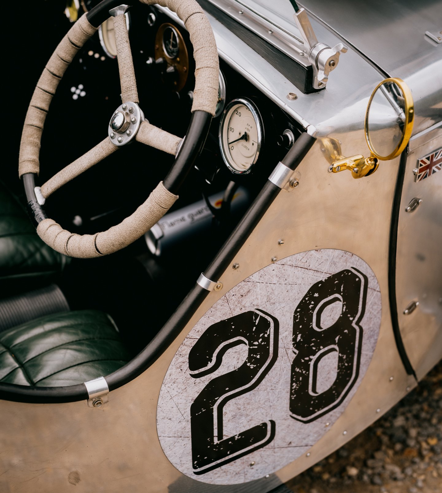 A close up of the steering wheel and livery of a classic austin racing car with the number 28 clearly visible