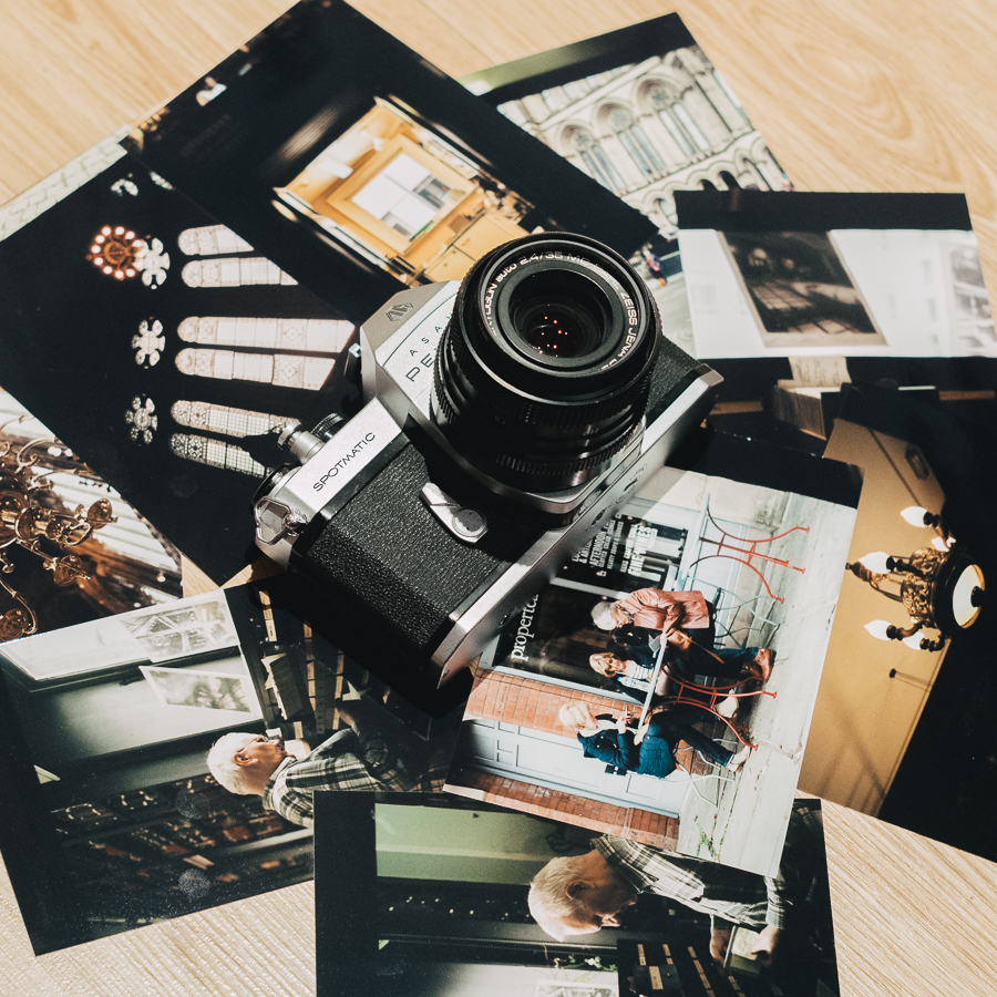 A photo of Pentax spotmatic on top of a selection of photo prints